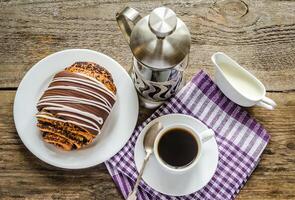 Tasse von Kaffee und Mohn Brötchen glasiert mit Ganache foto