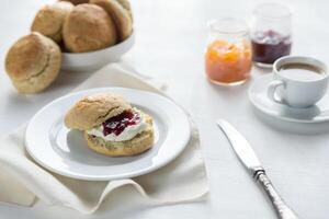 Scones mit Sahne und Obst Marmelade und Tasse von Kaffee foto