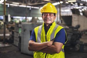 Porträt von ein männlich Ingenieur Stehen im Fabrik und Arm Kreuz suchen beim Kamera foto