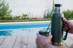 jung Mann Trinken Kamerad im das Morgen im Vorderseite von das Schwimmbad. foto