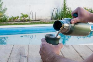 jung Mann Trinken Kamerad im das Morgen im Vorderseite von das Schwimmbad. foto