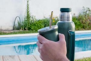 jung Mann Trinken Kamerad im das Morgen im Vorderseite von das Schwimmbad. foto