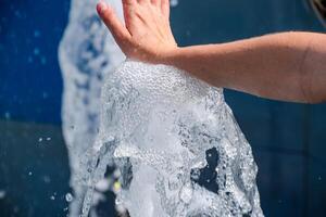 Hand berühren das Brunnen. ein Strom von Wasser von das Brunnen ist berührt durch Hand foto