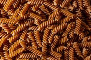 ungekocht ganze Korn Fusilli Pasta. ein kulinarisch Segeltuch von ganze Weizen Spiralen, Erstellen ein lebhaft und texturiert Hintergrund zum Gourmet Kochen. ganze Korn verdrehte trocken Pasta. ganze Weizen roh Makkaroni foto