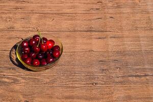 Beeren von ein Süss Kirsche im ein Glas Schüssel auf ein hölzern Hintergrund. reif rot Süss Kirsche foto