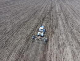 Anbau von Boden zum das Aussaat von Getreide. Traktor pflüge das Boden auf das Feld foto