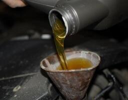 Öl Veränderung im das Motor von das Wagen. Füllung das Öl durch das Trichter. Auto Instandhaltung Bahnhof. foto