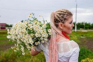 jung Mädchen mit ein Strauß von Gänseblümchen im Feld. Gänseblümchen auf ein Mohn Feld. foto