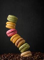 Stapel von mehrfarbig Macarons auf ein Hintergrund von Kaffee Bohnen, schwarz Hintergrund foto