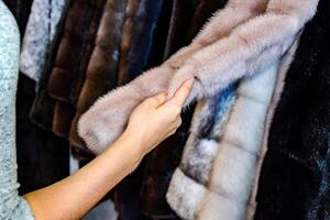 das Mädchen berührt das Pelz auf das Pelz Mantel. wählen ein Pelz Mantel im das Geschäft foto