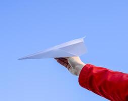 Weiß Papier Flugzeug im Hand gegen das Himmel. ein Symbol von Freiheit auf das Internet foto