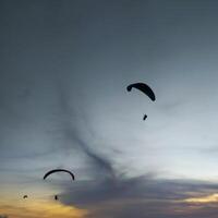 Silhouette von ein Gleitschirm hochfliegend im das Nachmittag Himmel. extrem Sport. foto