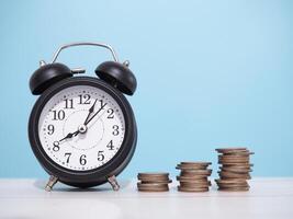 schwarz Alarm Uhr und Stapel von Münzen. das Konzept von Speichern Geld, verwalten Zeit zu Geschäft Leistung Ziel, finanziell, Investition und Geschäft wachsend foto
