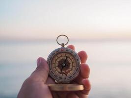 schließen oben Hand halten Kompass mit Strand Hintergrund foto