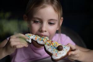 Kind Essen Ostern Hase geformt Lebkuchen Plätzchen dekoriert mit Glasur, Zucker Sträusel und Schokolade Hase Schwanz foto