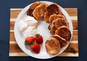 Erdbeere Krapfen mit sauer Sahne auf ein Weiß Teller und ein Tafel zum Frühstück, foto