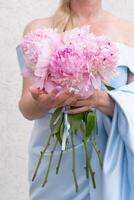 Braut im ein Blau Hochzeit Kleid mit ein Strauß von Rosa Pfingstrosen, Pastell- Paradies foto