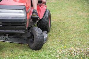 Rasen Mäher mäht das Gras, ein mittleren Alters männlich Gärtner funktioniert auf ein Mini Traktor foto