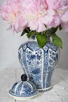 Rosa luxuriös Pfingstrosen im ein uralt Chinesisch Vase mit Blau Ornament, Frühling foto