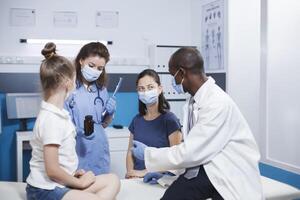 gemischtrassig Gesundheitswesen Arbeitskräfte empfehlen ein Flasche von Tabletten wie Wiederherstellung Behandlung zu Mutter von ein klein Kind im Kabinett. Arzt geben Flasche mit Rezept Medizin zu ein Frau mit ein wenig Mädchen. foto