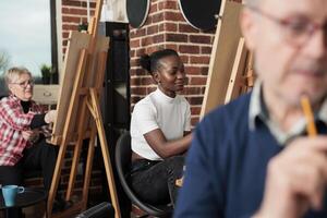 vielfältig Menschen von anders Alter Lernen zu zeichnen zusammen während Gruppe Kunst Klasse. lächelnd afrikanisch amerikanisch tausendjährig Mädchen Zeichnung auf Leinwand, bekommen kreativ mit Familie und freunde im Kunst Studio foto