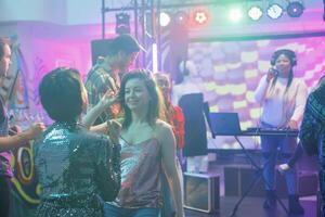 Freundinnen reden während entspannend auf Tanzfläche beim Nachtclub Diskothek. lächelnd Frauen Tanzen zusammen während Party machen und Teilnahme Leben elektronisch Musik- Konzert im Verein foto
