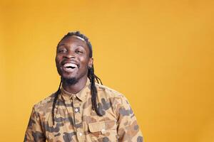 Porträt von afrikanisch amerikanisch Mann lächelnd während Fotoaufnahme, lachend beim Kamera im Studio Über Gelb Hintergrund. entspannt heiter Person haben positiv Gesichts- Ausdruck, posieren zuversichtlich foto
