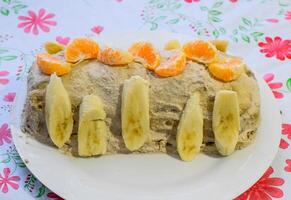 Kuchen mit Banane und Mandarinen, bestreut mit Schokolade. foto