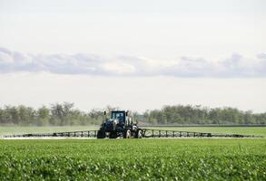 Traktor mit ein sprühen Gerät zum fein dispergiert Dünger. foto