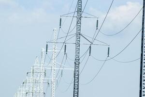 unterstützt Hochspannung Leistung Linien gegen das Blau Himmel mit Wolken. elektrisch Industrie foto