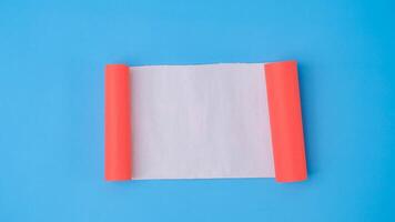 ein Orange gerollt Platz Papier ist Verbreitung aus in ein leer Weiß Blatt auf ein Licht Blau Hintergrund. zerknittert leer Weiß Papier mit Kopieren Raum zum Text oder Werbung Raum. foto