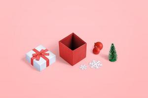 süße geöffnete Weihnachtsgeschenkbox mit mehreren Dekorationen auf pastellrosa Hintergrund