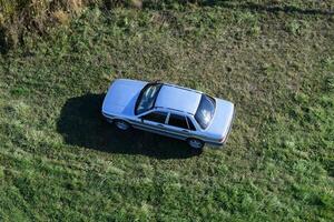 oben Aussicht von ein Silber Auto Stehen auf das Rasen. einer geflogen Über das Wagen. foto