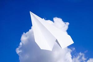 Weiß Papier Flugzeug im ein Blau Himmel mit Wolken. das Botschaft Symbol im das Bote foto