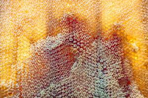 Tropfen Bienenhonig tropfen aus sechseckigen Waben, die mit goldenem Nektar gefüllt sind foto