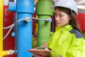 Instandhaltung Techniker beim ein Heizung Anlage, Petrochemie Arbeitskräfte überwachen das Betrieb von Gas und Öl Pipelines im das Fabrik, Ingenieure stellen Hören Schutz beim Zimmer mit viele Rohre foto