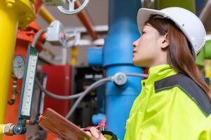 Instandhaltung Techniker beim ein Heizung Anlage, Petrochemie Arbeitskräfte überwachen das Betrieb von Gas und Öl Pipelines im das Fabrik, Ingenieure stellen Hören Schutz beim Zimmer mit viele Rohre foto