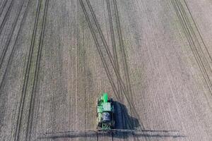 Traktor mit aufklappbar System von Sprühen Pestizide. düngen mit ein Traktor, im das bilden von ein Aerosol, auf das Feld von Winter Weizen. foto