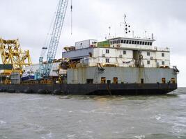 das Ladung Schiff mit das Kran, das oben Sicht. Rohrverlegung Lastkahn. foto