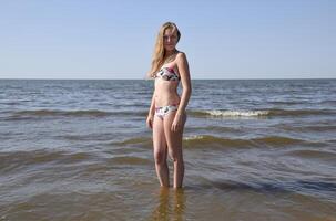 blond Mädchen im ein Bikini auf das Strand. schön jung Frau im ein bunt Bikini auf Meer Hintergrund foto