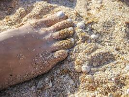 Damen Fuß mit gemalt Silber Fingernägel. Bein Stehen auf das Sand. Pediküre foto