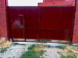Stahl rostig Tore und ein rot Backstein Zaun. foto