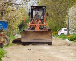 Grader auf ein Schmutz Kies Straße. Straße Reparatur durch Hinzufügen Schutt. foto