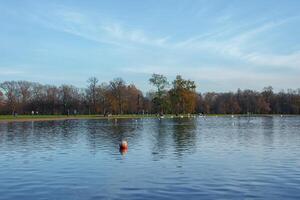 Erfahrung herbstlich Gelassenheit durch ein London See, mit Orange Boje und Bäume. foto