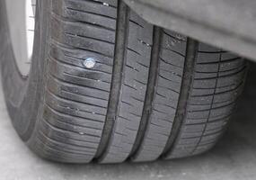 Metall Schrauben auf Auto Reifen niedrig Druck. Nahansicht von Auto Reifen durchbohrt mit Eisen Schrauben Reifen Reifenpanne auf schwarz Hintergrund mit Kopieren Raum. selektiv Fokus foto