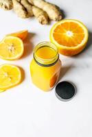 gesund Lebensstil Konzept. frisch Orange Saft im ein Glas Flasche mit Ingwer und Zitrone auf Weiß Hintergrund. foto