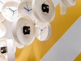 Nahansicht und Ernte Gruppe von schmücken modern Weiß Uhr Mauer hängen auf Mauer mit Nieder Beleuchtung im Show Zimmer. foto