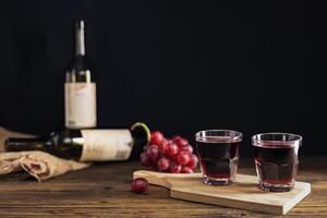 rot Traube Saft im ein Glas platziert auf ein hölzern Tabelle oder rot Wein, ein köstlich natürlich gesund Saft trinken. mit ein Bündel von frisch rot Trauben von das Garten foto