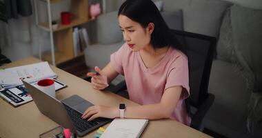 Porträt von jung Frau Sitzung beim das Schreibtisch und Arbeiten auf Laptop im Zuhause Büro foto