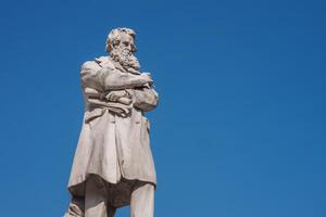 kontemplativ bärtig Mann Statue im lange Mantel gegen Blau Himmel Hintergrund im Venedig. foto